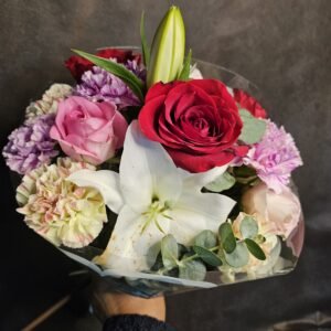 Ramo de flores con rosas, claveles, lirios y hojas verdes.