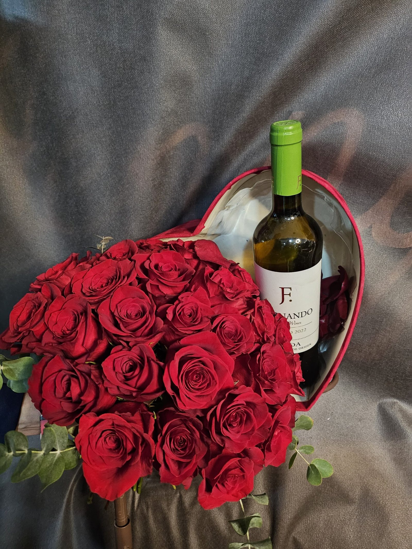 Ramo de rosas rojas con caja en forma de corazón y vino