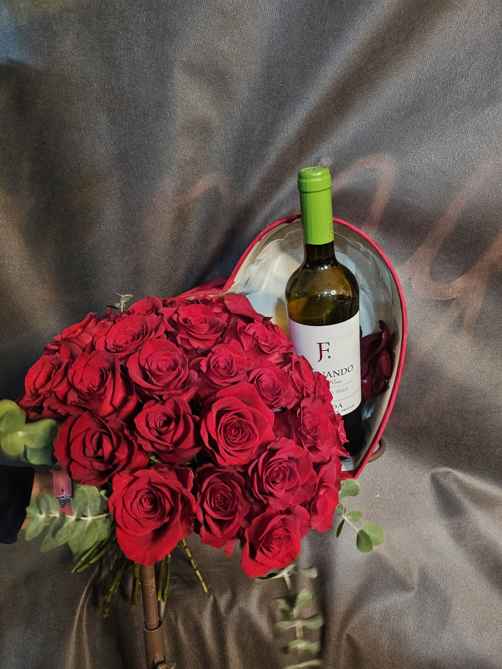 Ramo de rosas rojas con caja en forma de corazón y vino