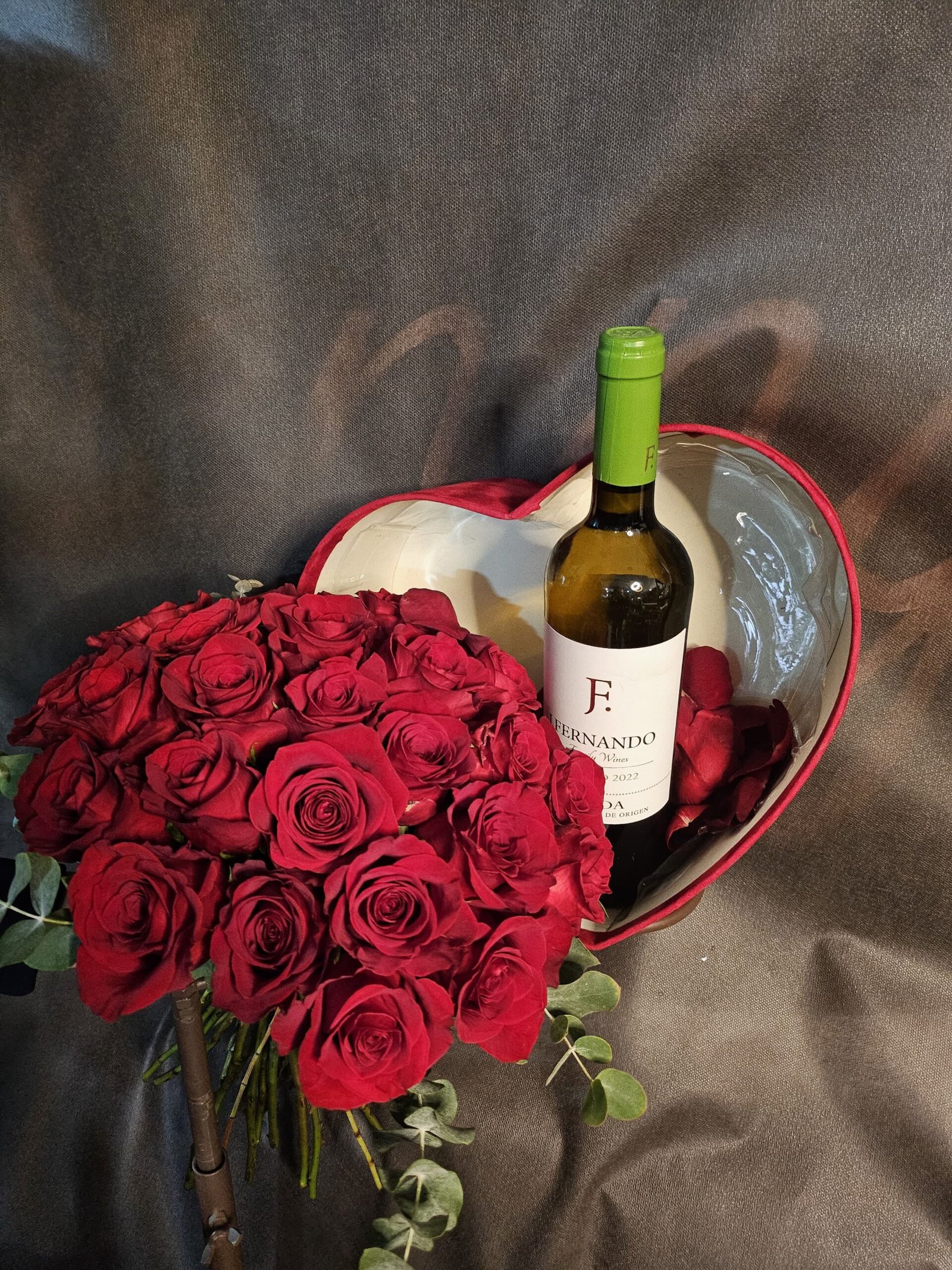 Ramo de rosas rojas con caja en forma de corazón y vino