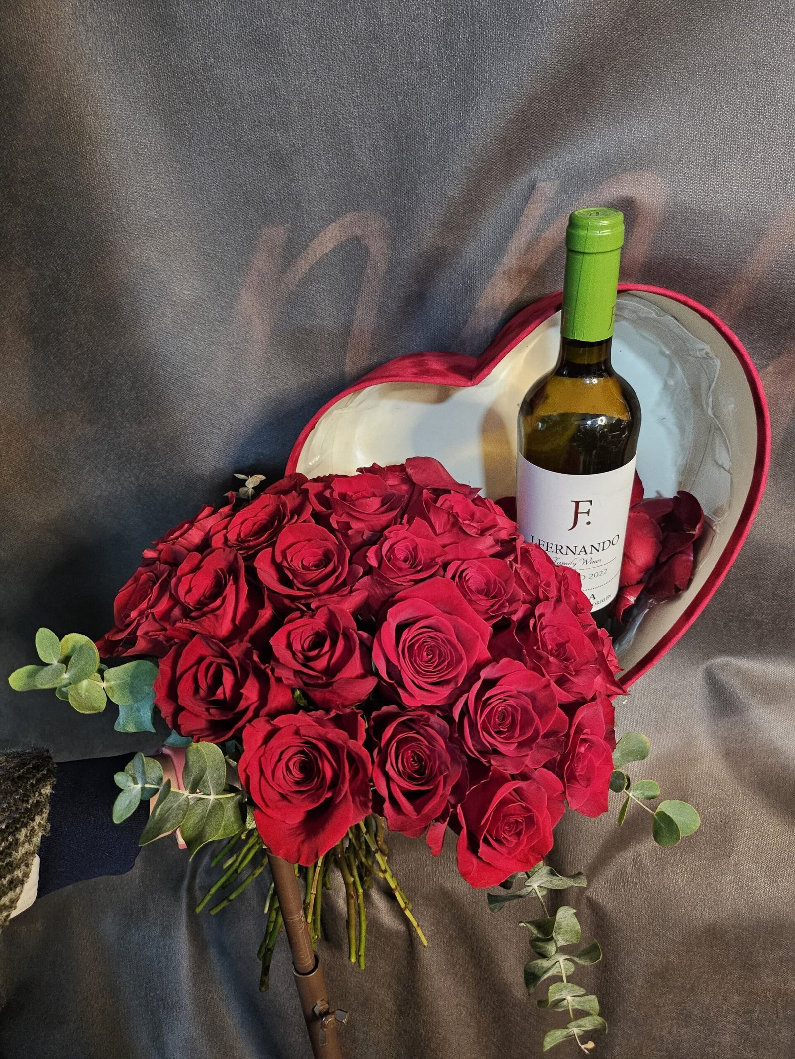Ramo de rosas rojas con caja en forma de corazón y vino