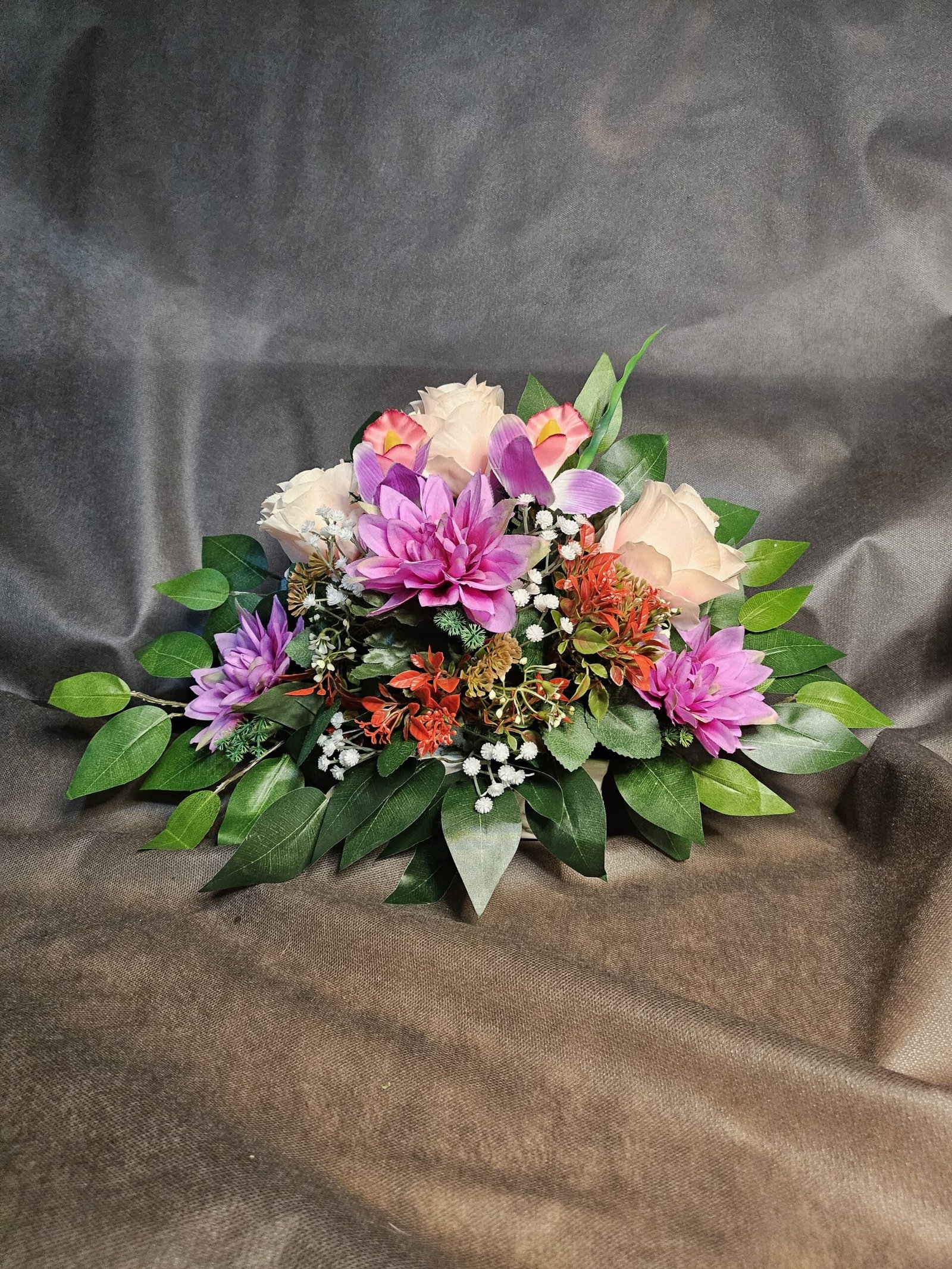 Rosas en tono pastel, flores moradas, blancas y naranjas, además de follaje verde.